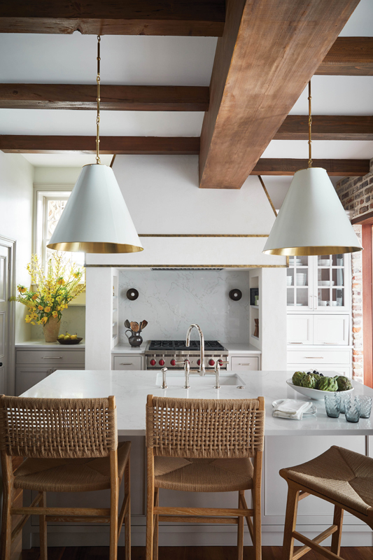 The large island provides ample counter space, and the white and brass “Goodman” pendants from Visual Comfort tie everything together with a modern feel.