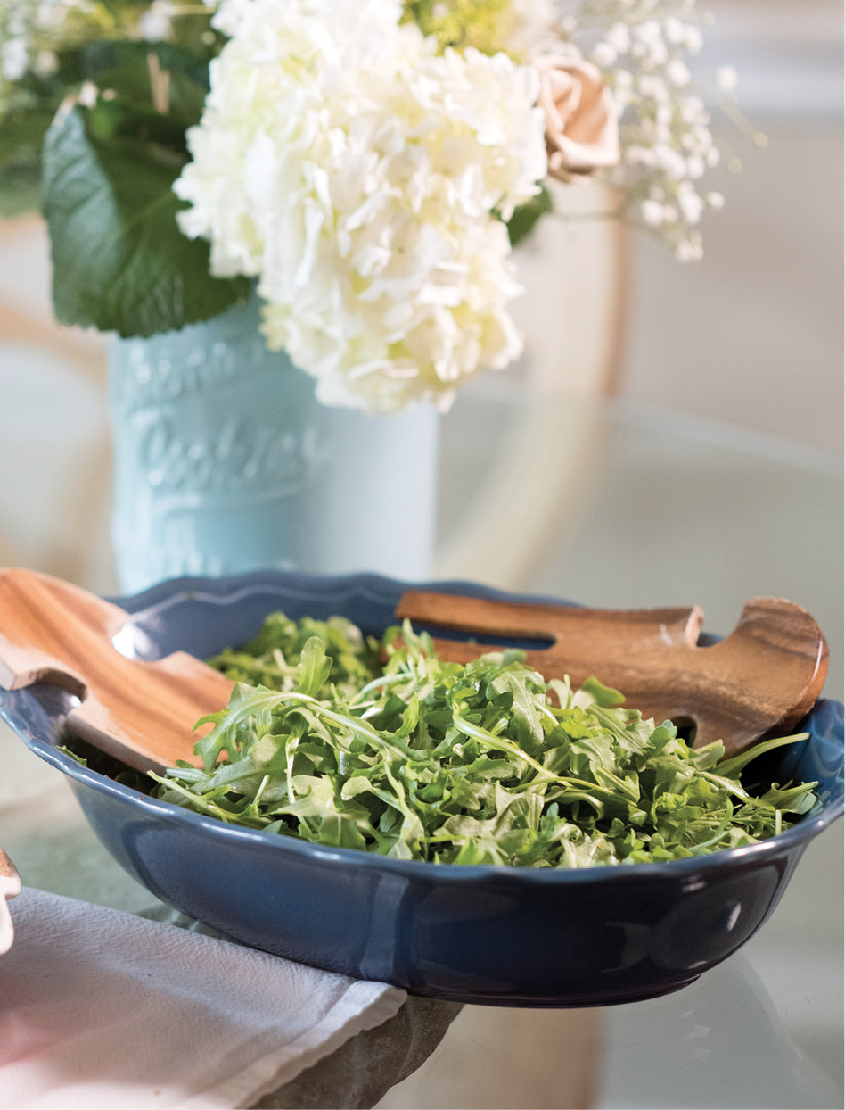 Arugula gets tossed with a bright dressing composed of spring onions, olive oil, mustard, white wine, champagne vinegar, garlic, and capers.
