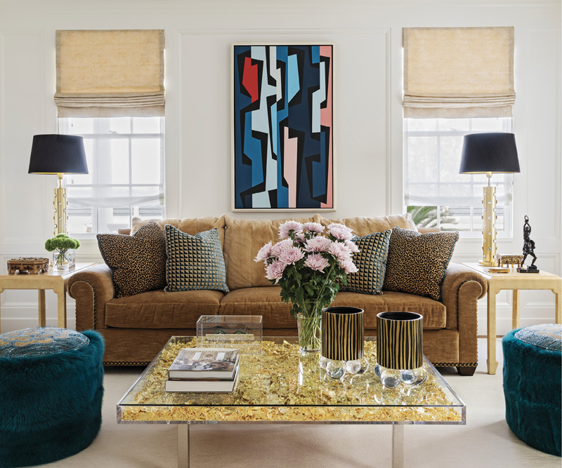 A dazzling Yves Klein coffee table made with 3,000 sheets of gold leaf sits in front of the Coco Chanel-inspired sofa upholstered in a warm Kirkby fabric and accented by Sabina Fay Braxton and Scalamandré fabric on the throw pillows. A Karl Benjamin oil painting above the sofa adds a pop of color, and a pair of Jean de Merry “Lora” chairs and two ottomans embroidered with Chanel’s favorite flower, camellias, ━ provide more places to perch and admire the decor.