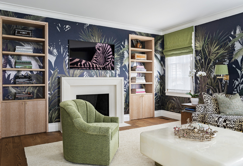 The “Jungle Room” pairs a bold Phillip Jeffries wallpaper with touches of emerald green fabric in the chairs, lampshades, and window coverings. A lacquered goatskin coffee table by Karl Springer on a cream Mark Nelson Designs area rug softens the drama of the room.