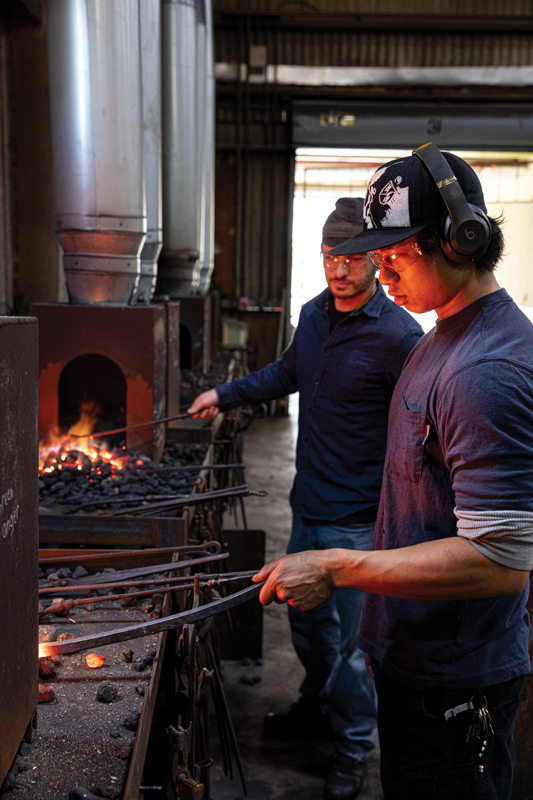 Blacksmithing professor Abe Pardee works with ACBA senior Emmett Sullivan; the school will unveil its new forge on upper King Street this month.