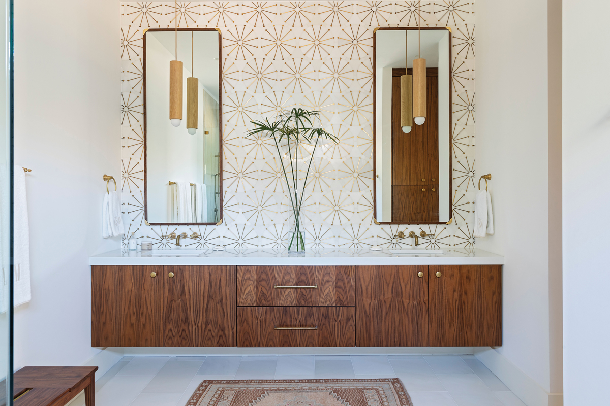 A wall of polished mosaic marble from Italy provides a similar statement piece in the en-suite bathroom, where custom mirrors from Artisan Woodworks reflect elegant Workstead “Tower Pendants.”