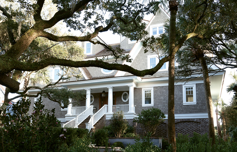 The front entrance to the shingle-style abode is shaded by old-growth oaks.