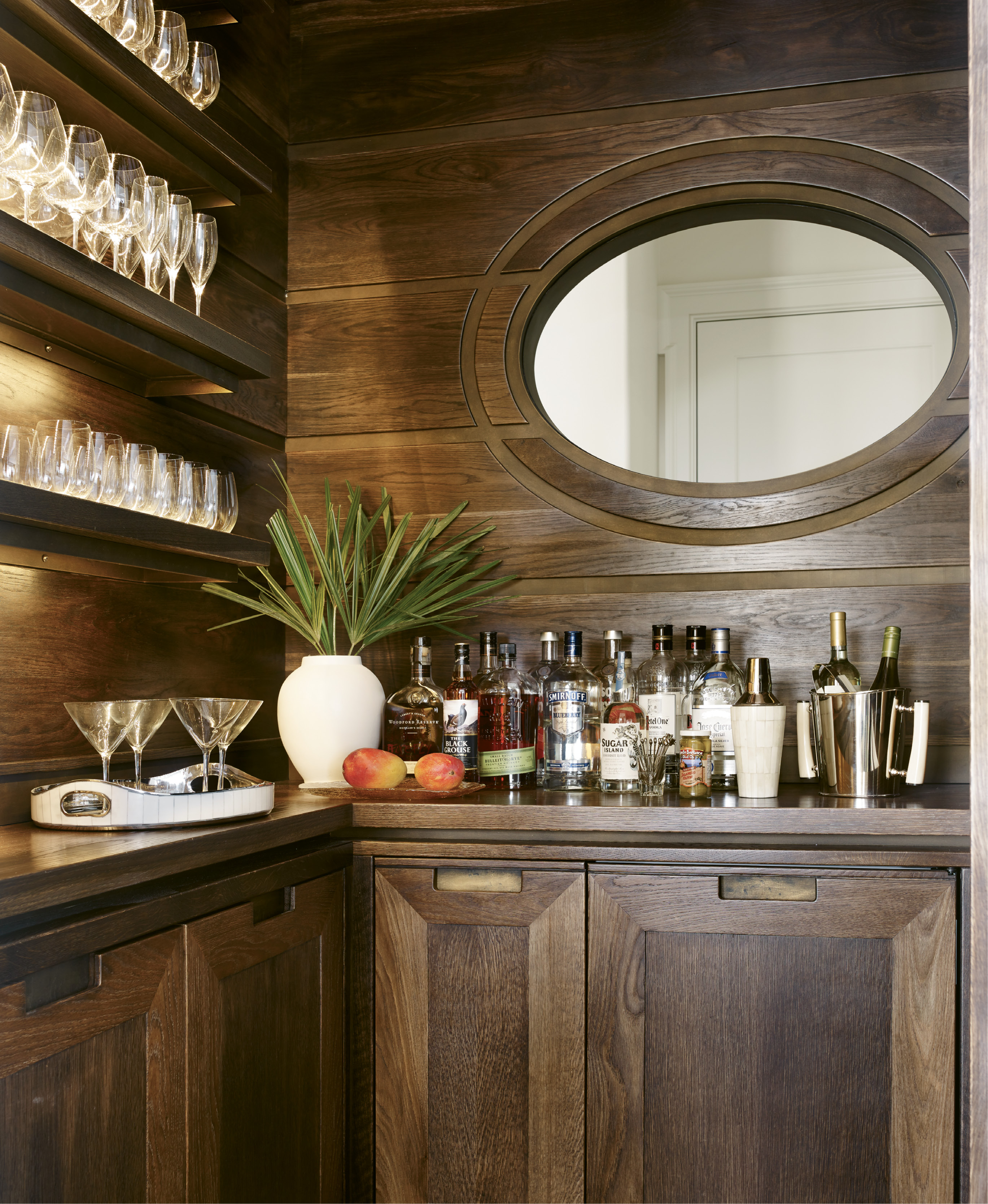 Custom cypress cabinetry by local firm ECR Joinery and an oval-shaped interior window distinguish the bar, which separates the kitchen and living room.