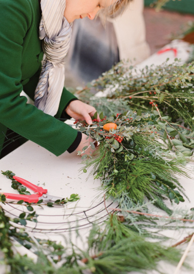 It’s best to layer on bundles of accent ingredients—like kumquats and ilex berries—before filling the form with greenery.