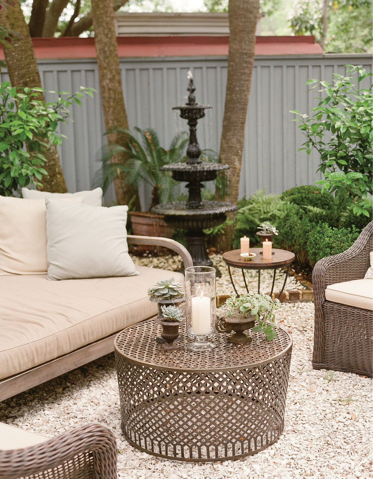 To turn a garden alcove into an inviting cocktail nook, Lynn arranged outdoor furniture and added candles and potted plants to enhance an oyster tabby patio.