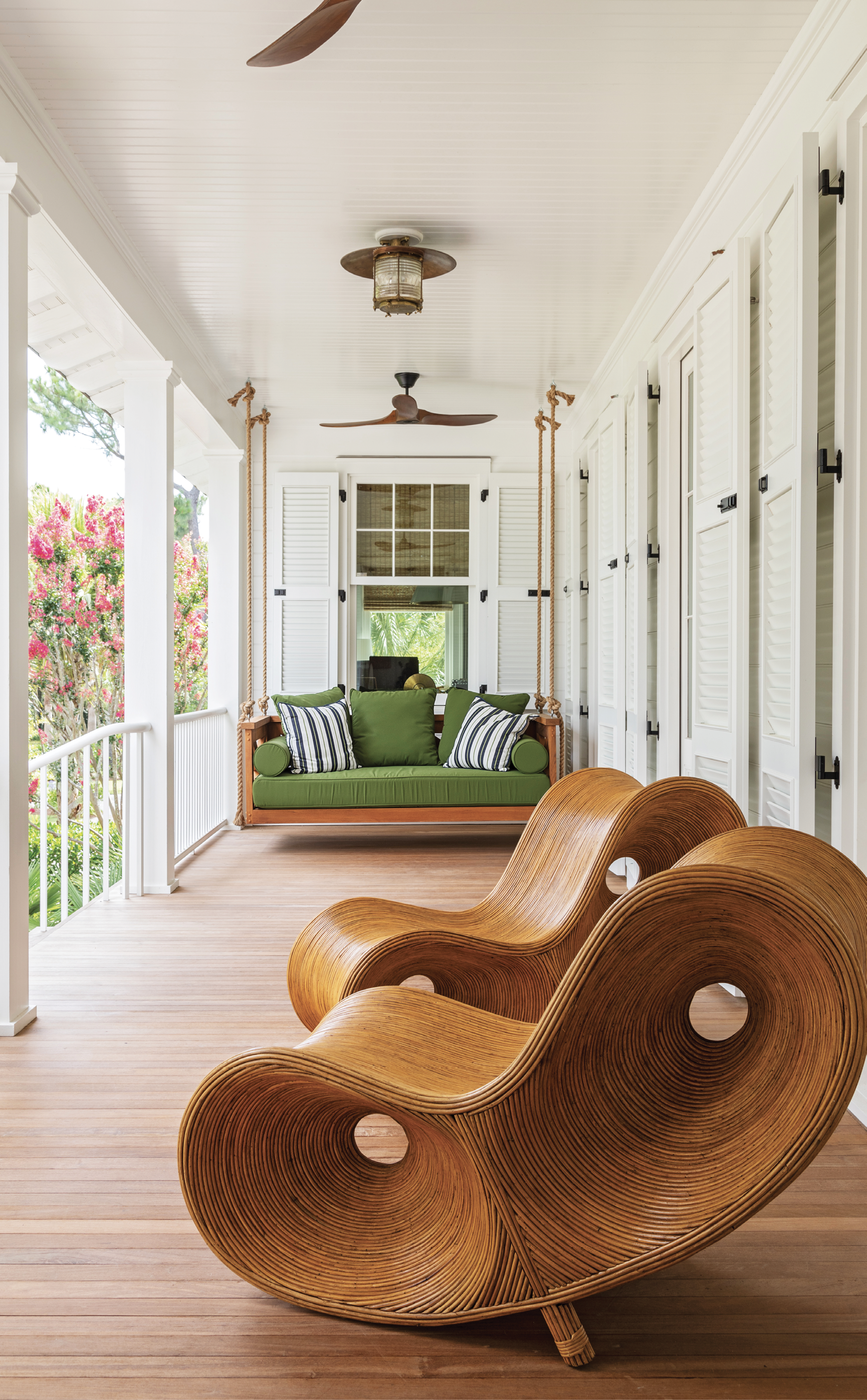 A swing is a must for a Lowcountry porch, and this one, covered in Sunbrella “Palm” canvas at the front entrance hints to the green and blue hues inside. The Rattan Infinity Loungers from Fritz Porter add a playful, artistic touch and the repurposed nautical light fixture brings in the vintage vibe.
