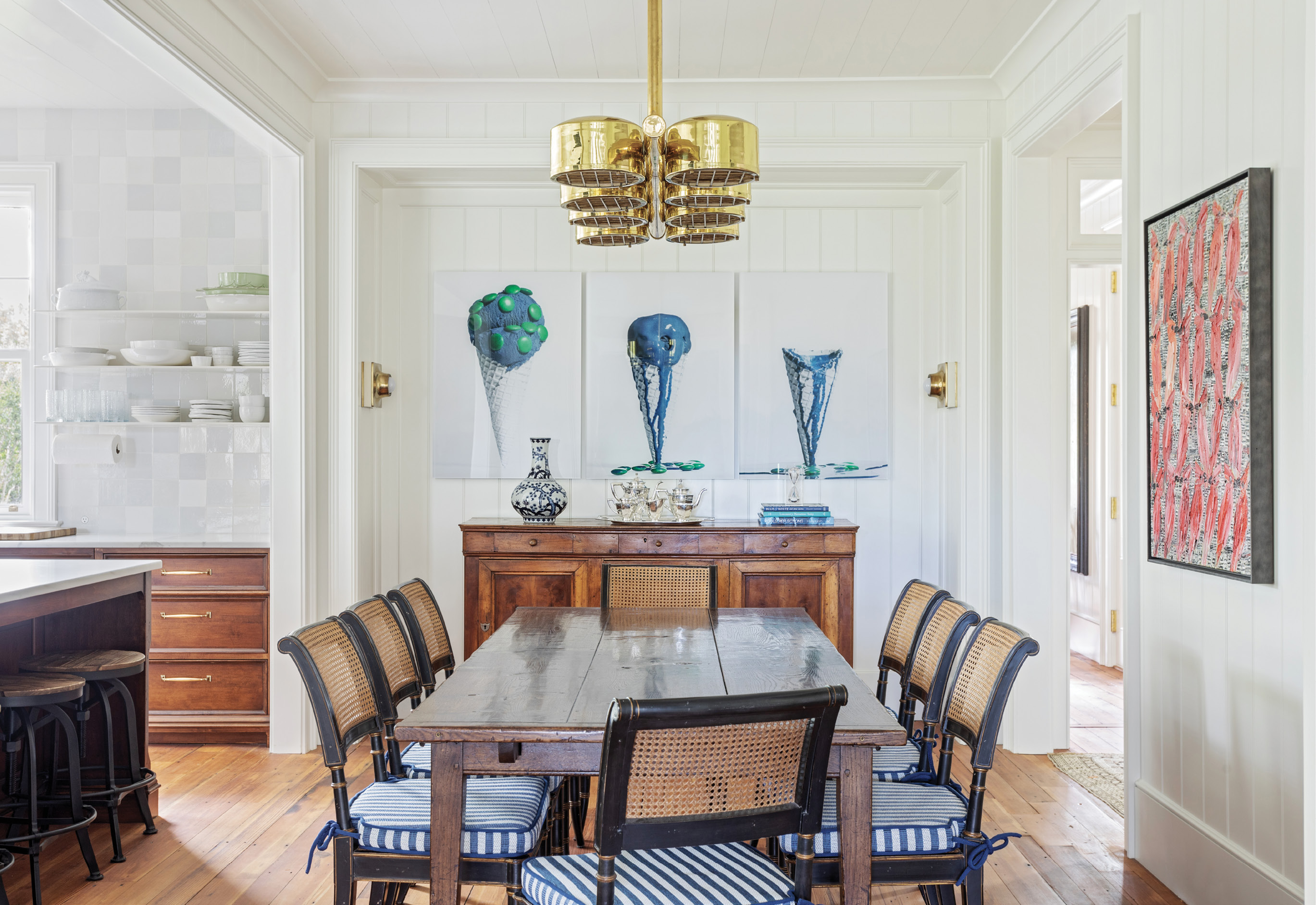 Thanks to the wife’s expert eye and quick fingers on 1stDibs.com, a treasure trove of vintage and antique light fixtures complements the interiors. In the dining room, both the nautically inspired chandelier and brass wall sconces were sourced from the site, the latter to illuminate the melting ice cream triptych, Picture Global Warming, by Swedish photographer Clara Hallencreutz.
