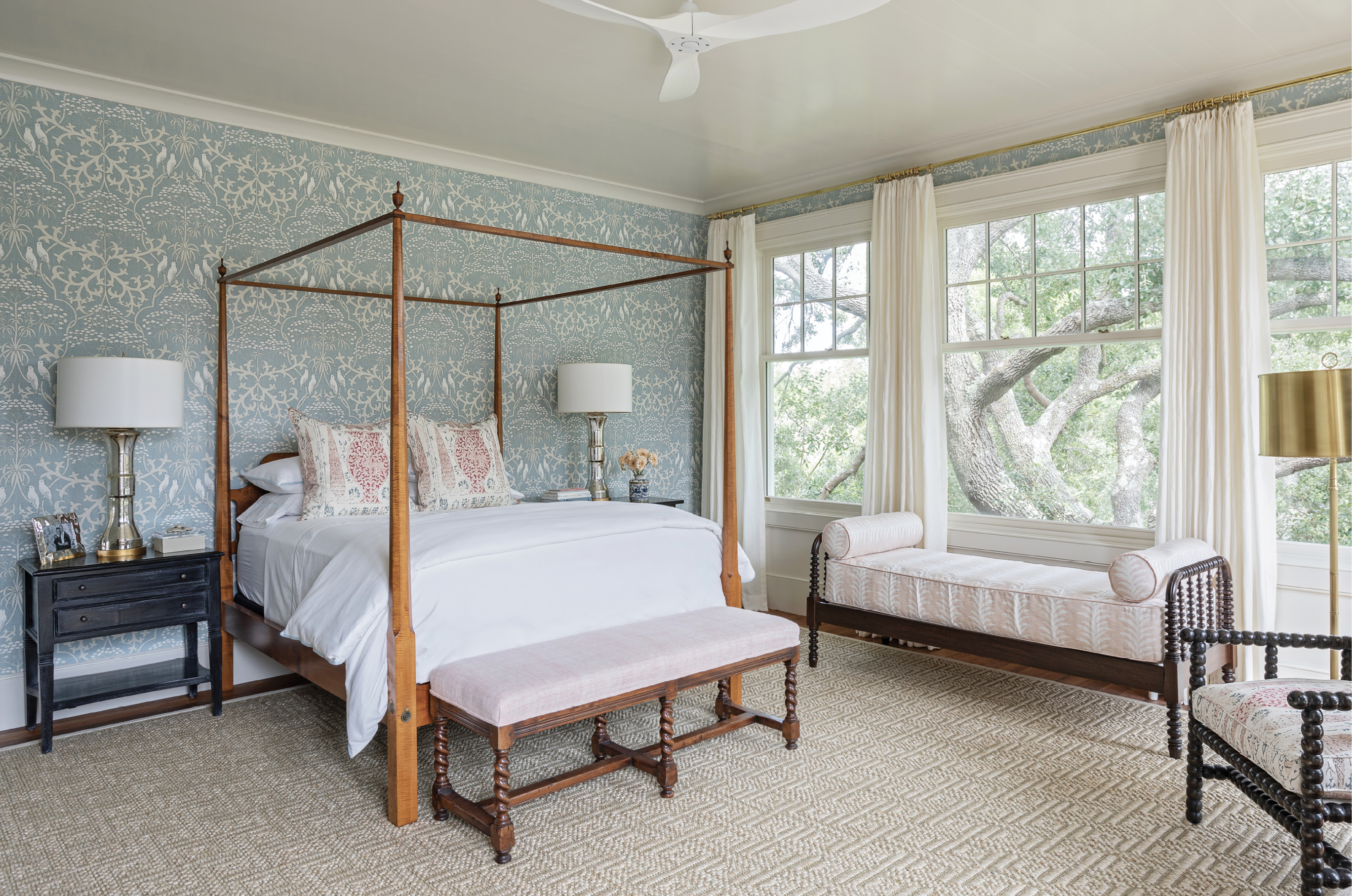 No art was needed in the owner’s bedroom once the architects’ expanded the room’s east-facing windows to bring in the natural beauty of its live oak neighbor. Dufford Young also removed smaller windows from the north wall creating the perfect space for the antique four-poster bed, which is accentuated by Penny Morrison “Vasari”-wrapped pillows and Lewis &amp; Wood “Bella” wallpaper from Fritz Porter.