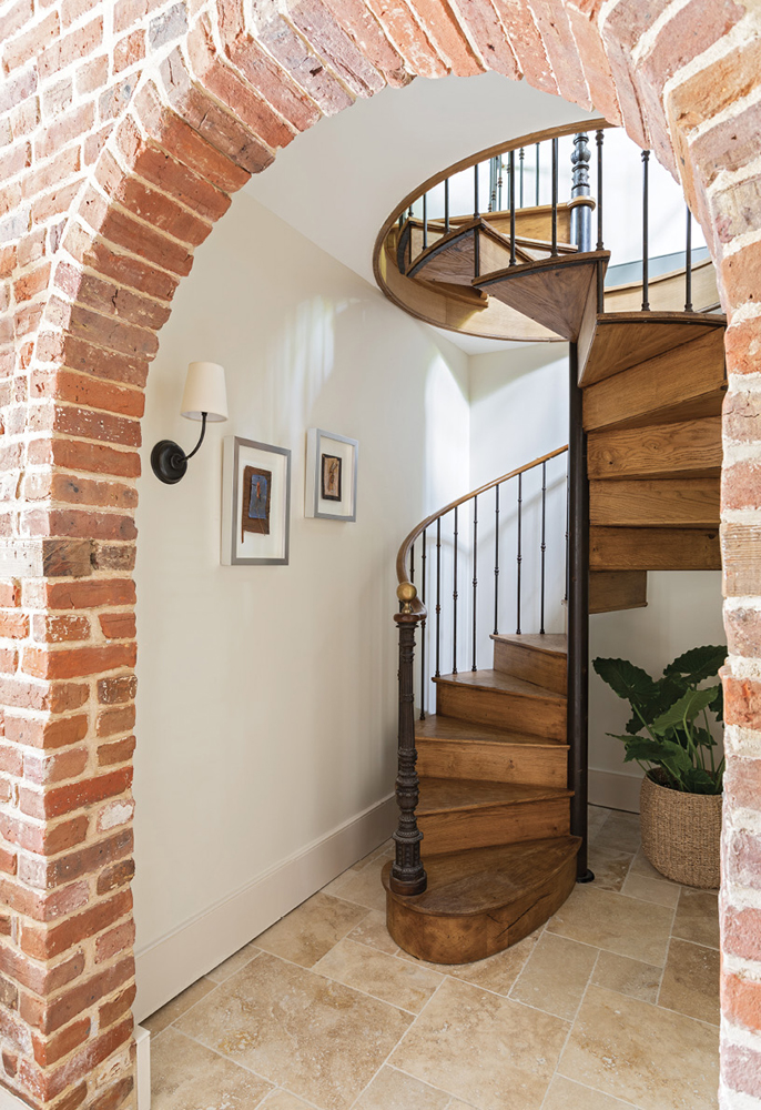 The brick walls and wooden beams are original to the carriage house, but this iron spiral staircase was imported from France to connect the two levels of the dependency during recent renovations.