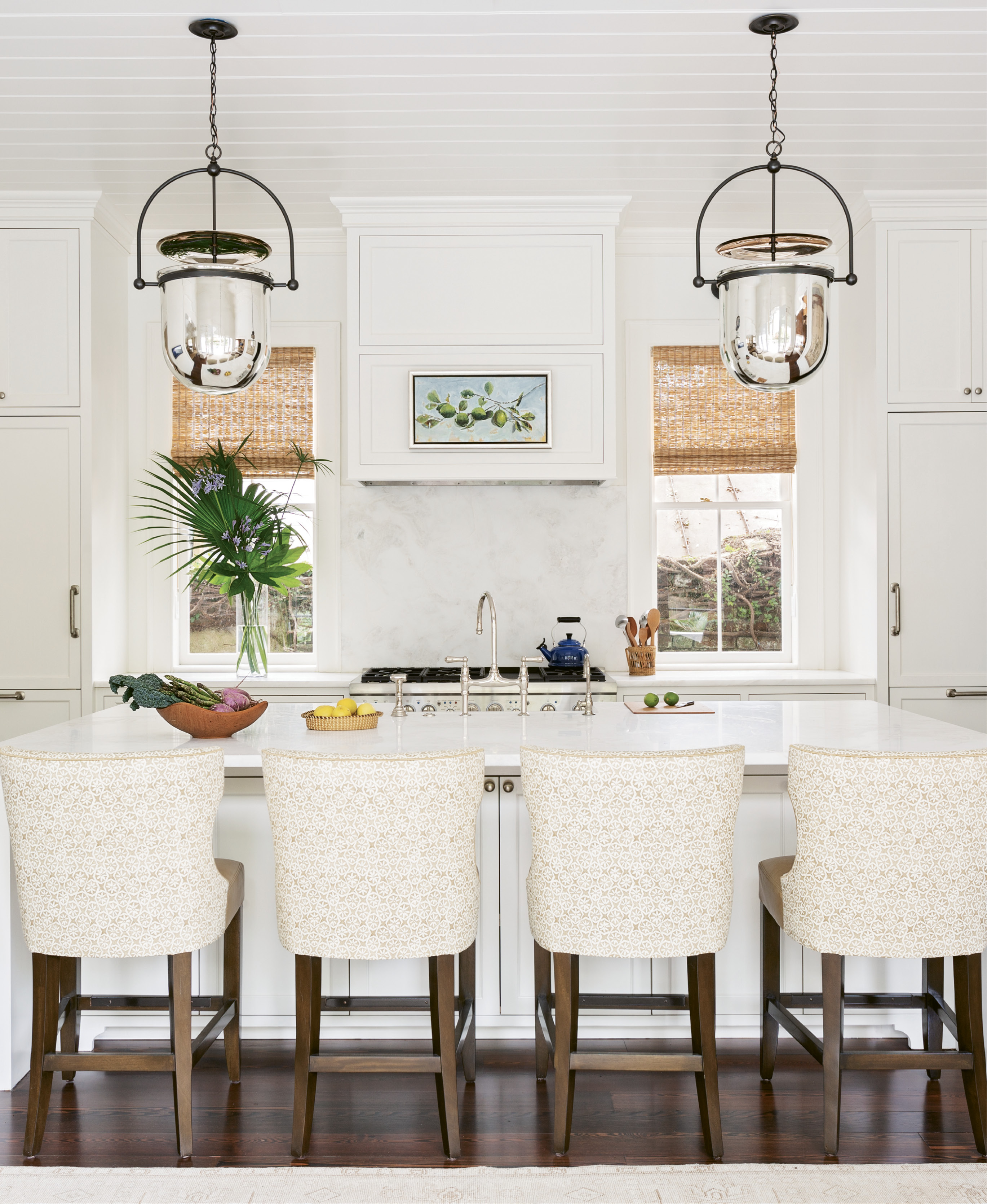 SIMPLE SYMMETRY: Dominated by a large white Namib marble-topped island, ideal for gathering the family as well as spreading out the newspaper, the kitchen is literally and figuratively the heart of this home. A pair of “Urban Smokebell” lanterns from Urban Electric add a grand scale and align perfectly with the two newly discovered windows, previously covered by cabinets.