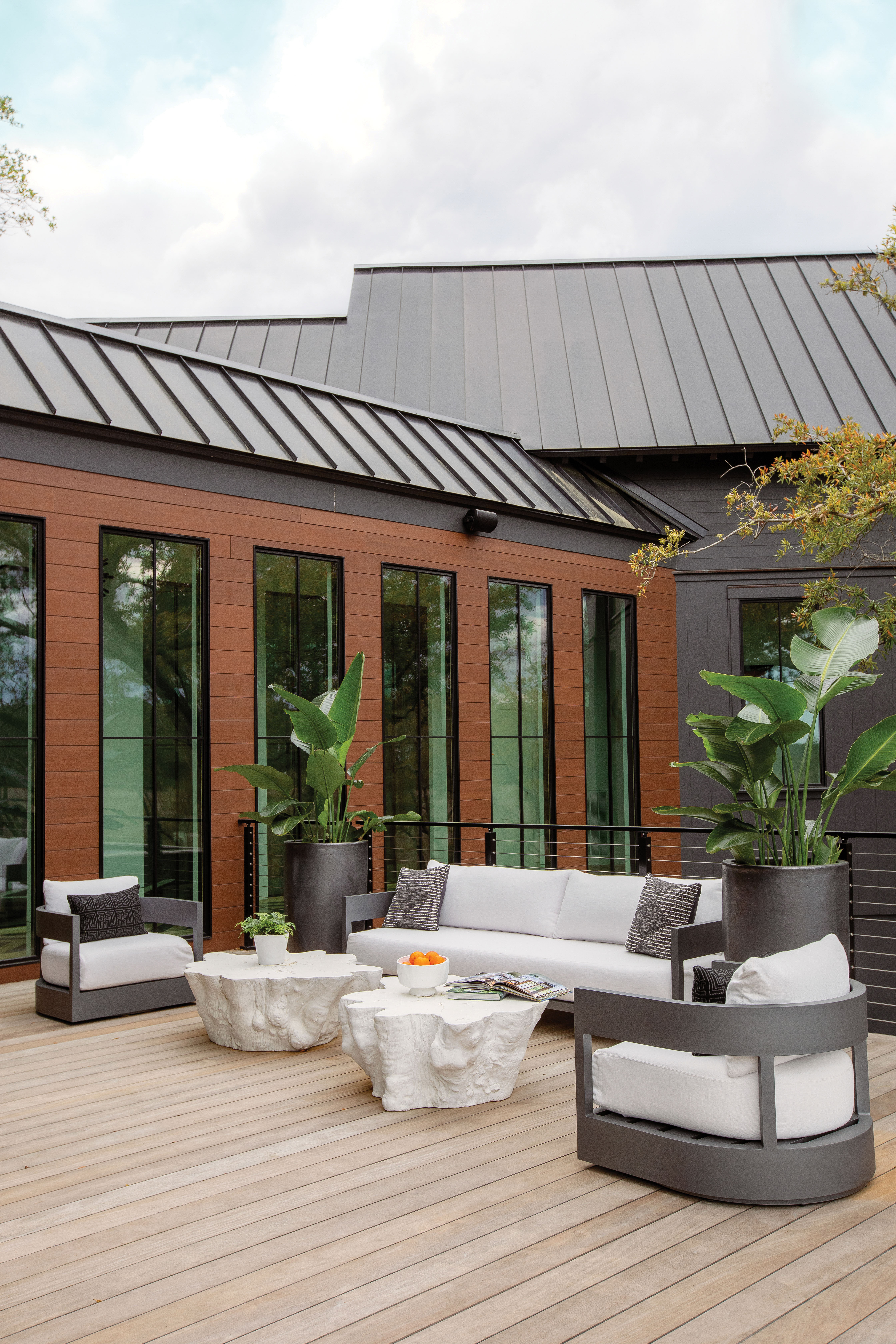 On Deck: Fiber cement siding that mimics the look of real wood with none of the maintenance issues brings warmth to the outdoor seating area, where Serena &amp; Lily “Boonville” coffee tables cast from real tree roots continue the organic look.