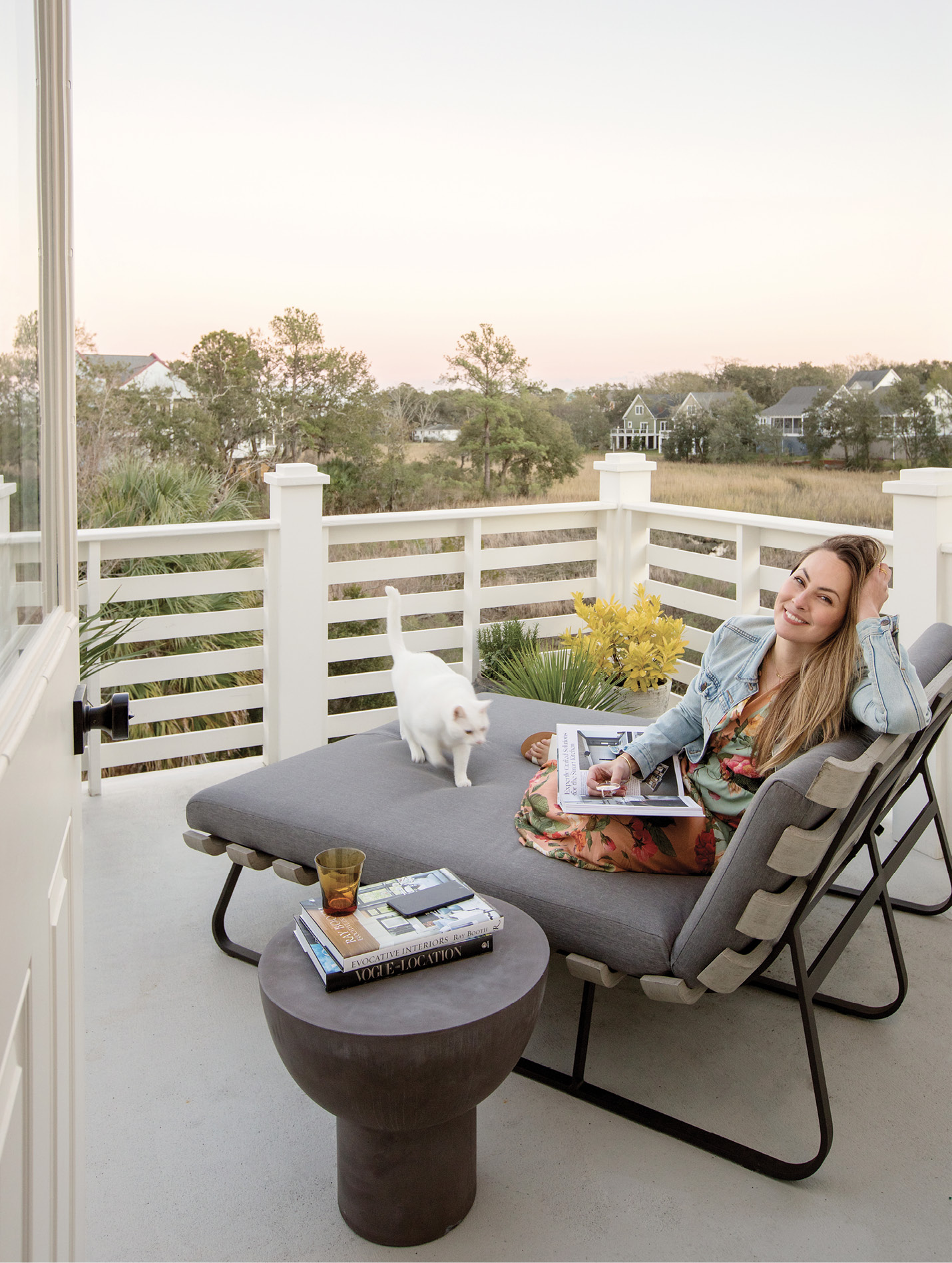 SEEKING SERENITY: It was the marsh view that drew Jesse Leigh Vickers to this North Charleston gem, and the top floor porch, outfitted with a double chaise by Four Hands and table by CB2, is the perfect place to read, relax, and soak up the scenery with her cuddly cat, Pickles.