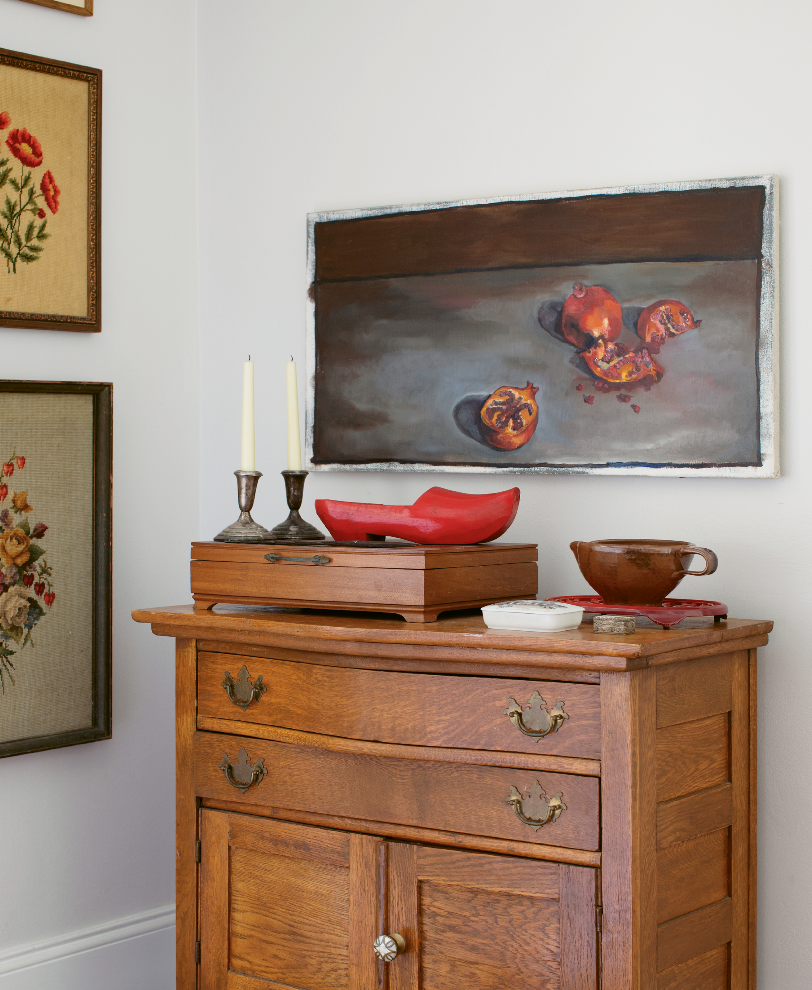 Jacques and Carrie Larson’s West Ashley home looks contemporary from the curb, but it’s filled with meaningful pieces from the past and present, like this pomegranate still-life by Carrie, needlepoints by Jacques’s grandmother, and a red clog carved by his great-grandfather.