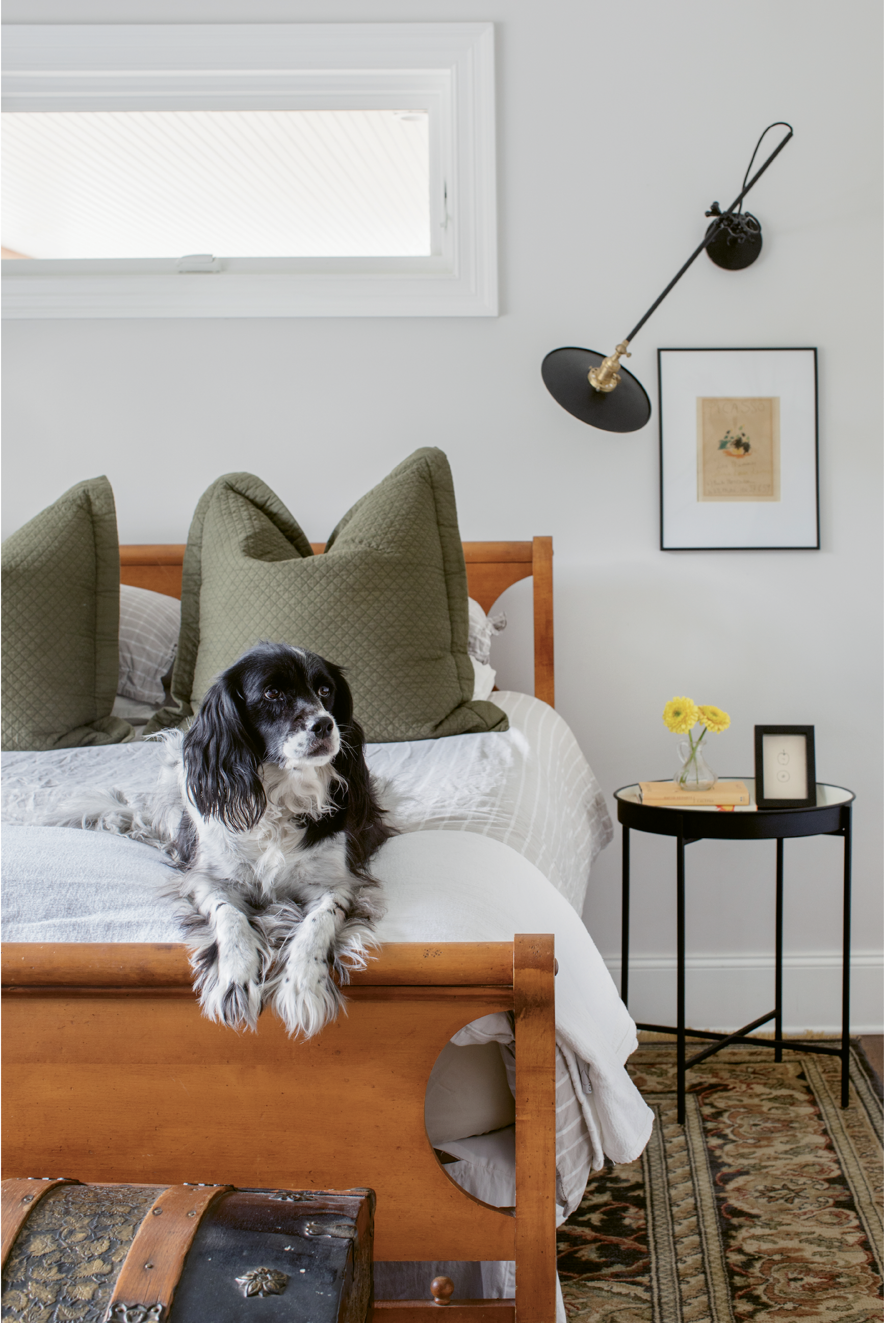 MIX, MASTERED: In the couple’s bedroom, a hand-me-down rug helps establish a color palette of earthy neutrals and olive greens; black accents, such as the sconce by Workstead, keep things grounded.