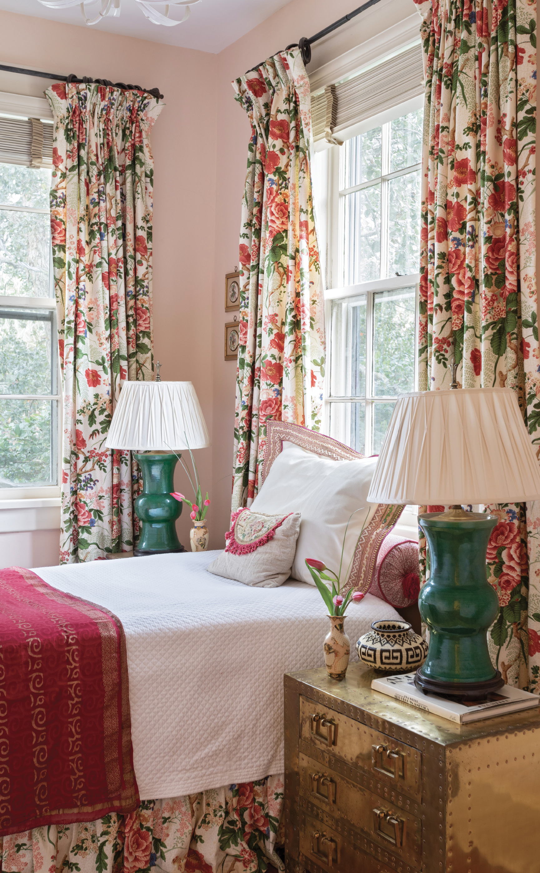 Pretty in Pink: This guest room came with the pretty chintz curtain and bed skirt, which the homeowner loved. Ralph made the space work around the colors in the fabric, adding vintage lamps and a Soane Britain pink bolster and painting the walls in “Queen Anne Pink” by Benjamin Moore.