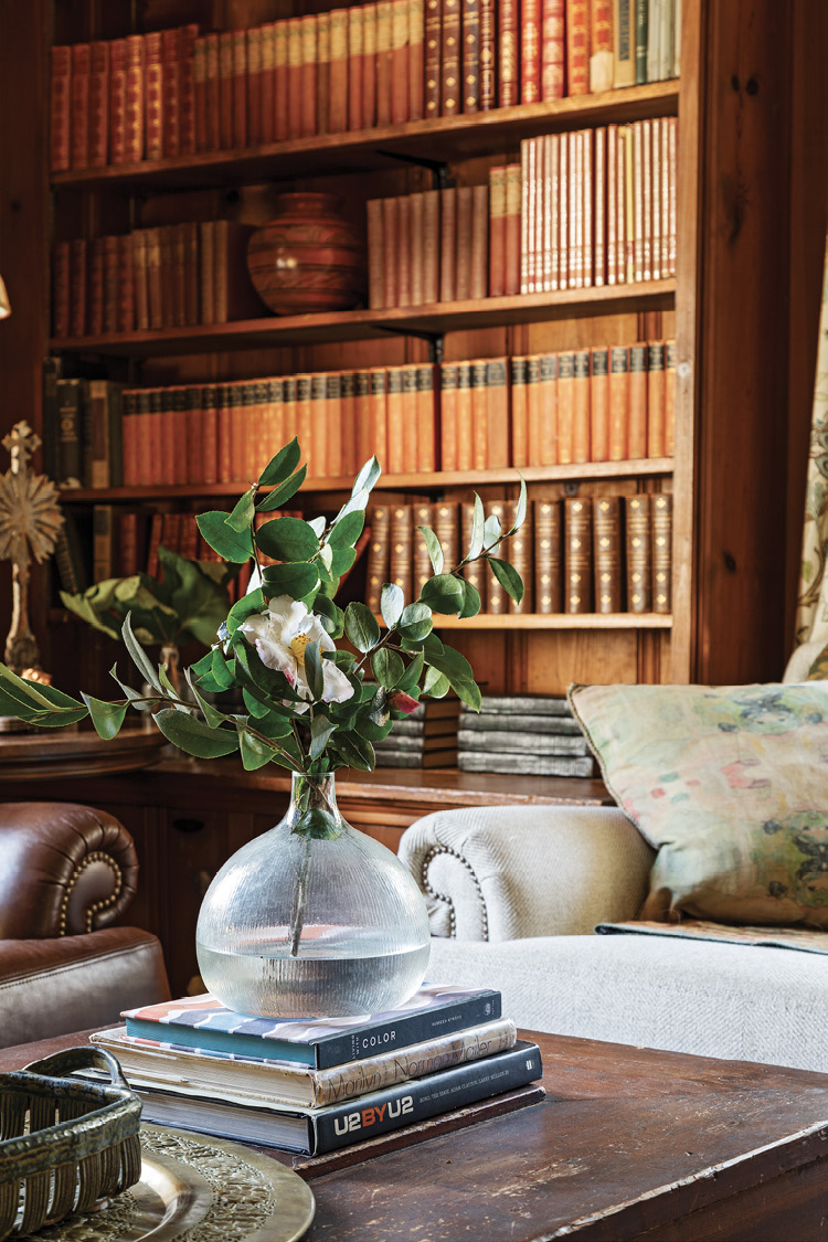 A Study in Contrasts: Details such as the red leather-bound volumes in the bookcase and the amber glass lamps flanking the leather sofa play up the tones of the wood paneling, whereas the crisp white sofa adds interest.