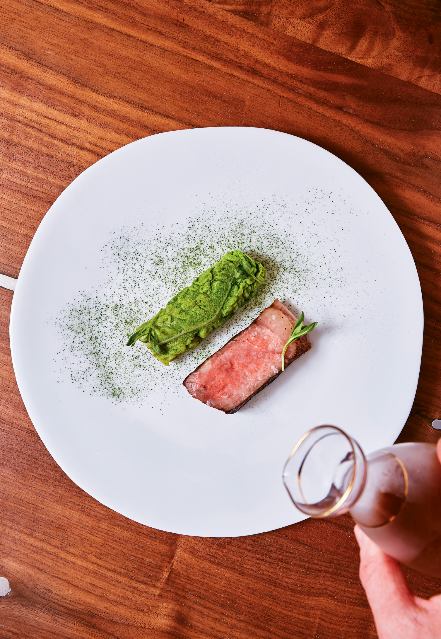 Worth the wait: Dry-aged beef is prepared on a Japanese Konro grill, which produces no sizzle or smoke while it gently sears and cooks the meat. A savoy cabbage leaf, stuffed with farro and kimchi, is served on the side.