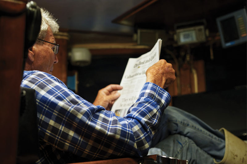 ...Captain Bubba Rector reads the paper as his trawler is on course for the day’s first shrimping destination, typically within six miles from shore.