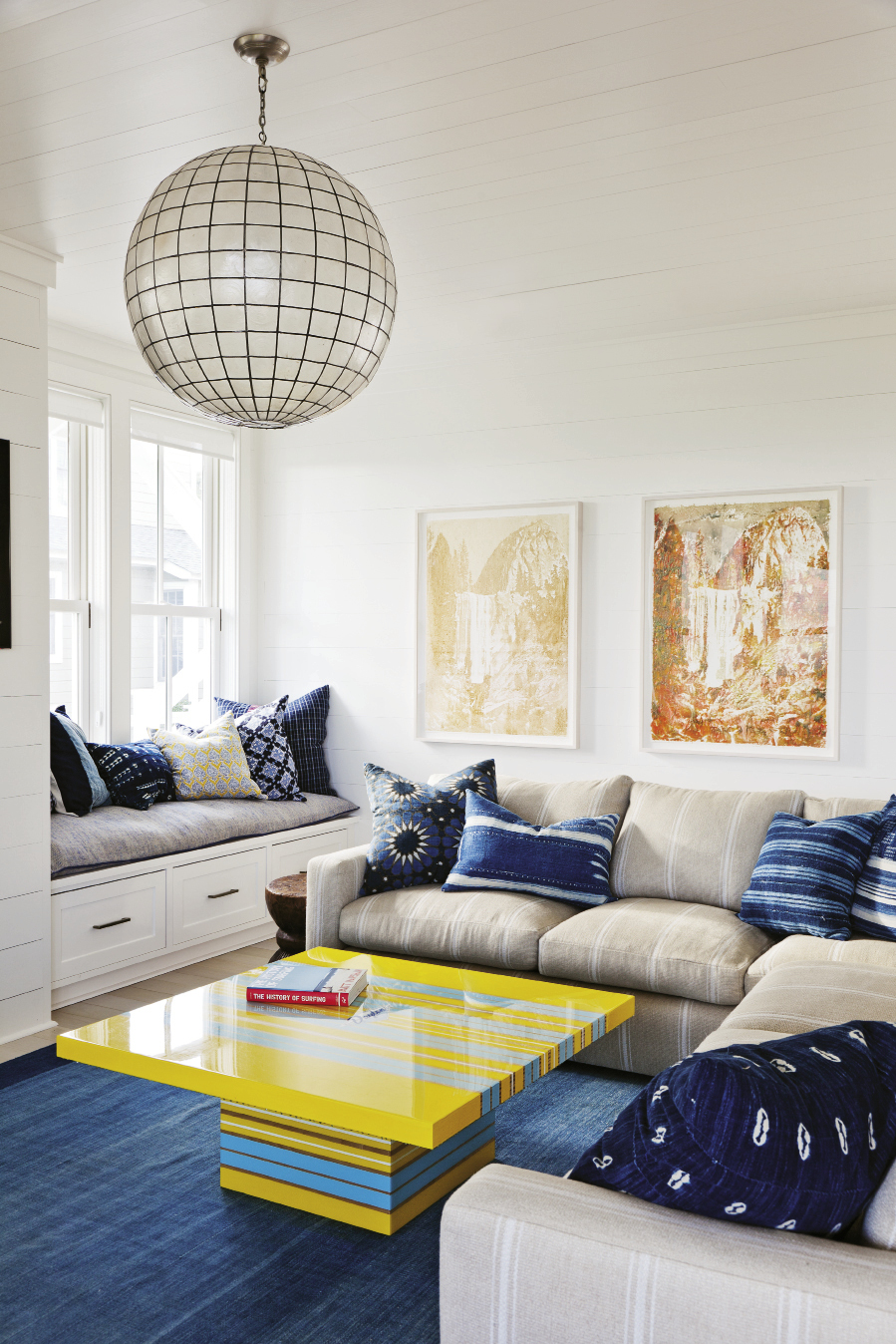 The family room hangs 10 with a bright yellow and blue surfboard-inspired table and an array of pillows made from vintage textiles. Delicious artwork by Matthew Brandt is made of Gummi Bears and Pixy Stixs.