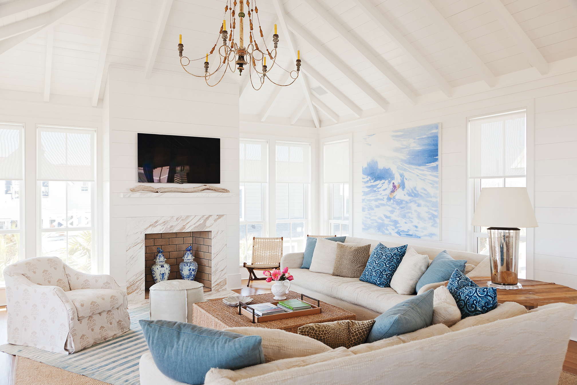 Old-School Charm: White shiplap walls throughout lend a classic beach-house feel while showcasing contemporary art, such as this surfer painting by Isca Greenfield Sanders in the living room.