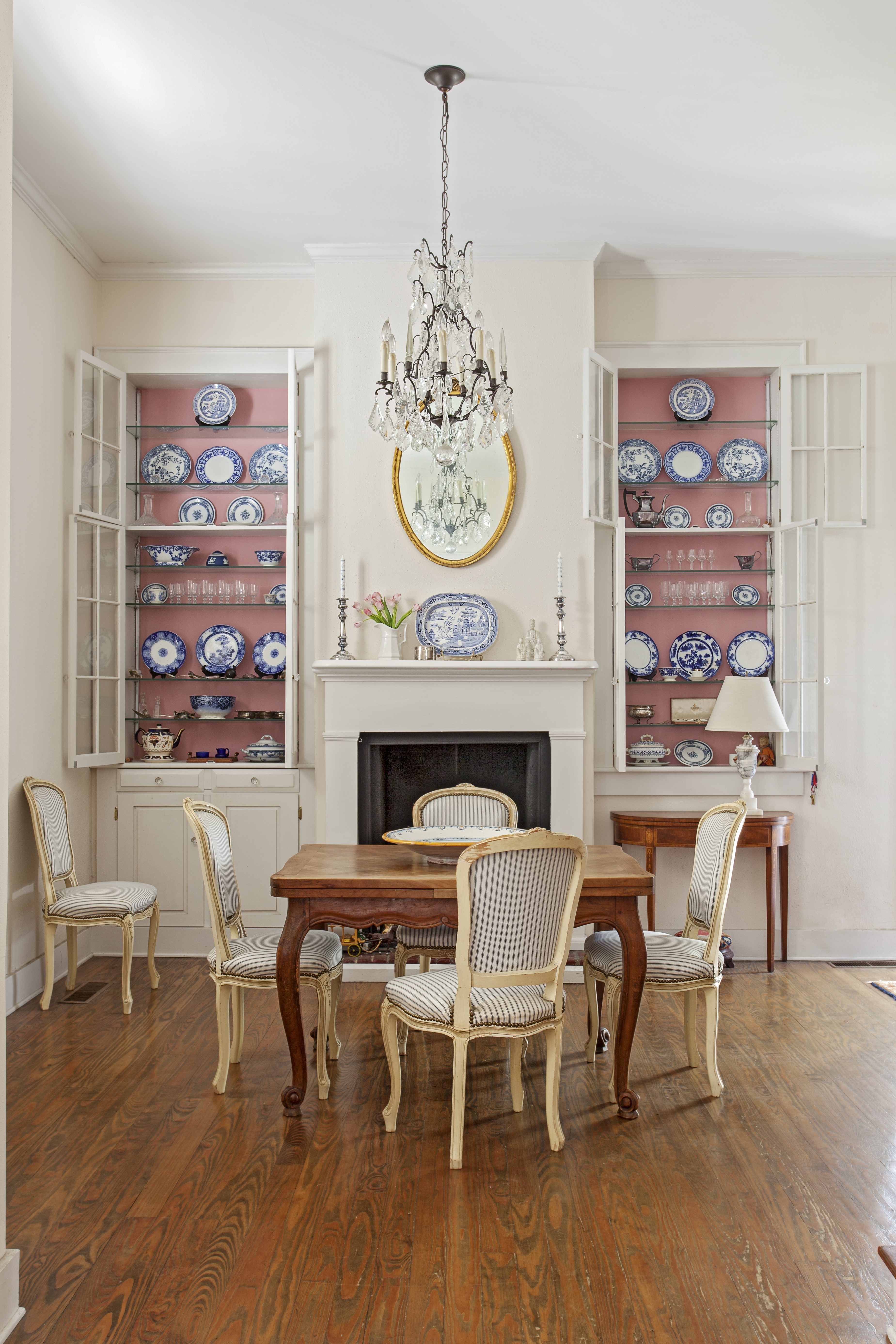 Display of Affection: Beloved collections of china (including Flow Blue and Blue Willow pieces) are on display in the dining room. Bigner added ticking to these chairs to balance their elegant shape with a more casual, inviting vibe.