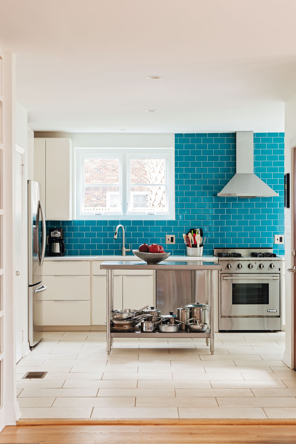 “COAT” d’AZUR: A wall of bright blue subway tile delivers a splash of color to the modernized kitchen, with new stainless steel appliances, custom cabinets, and Daltile countertops.