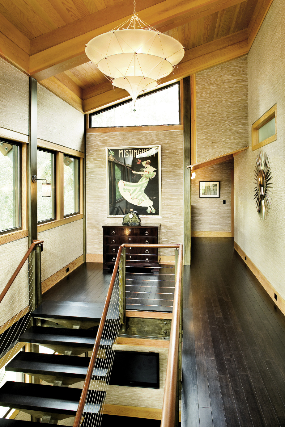 A bank of windows and a Fortuny  pendant shade ensure the upstairs hall—with its angled roofline—receives ample light.