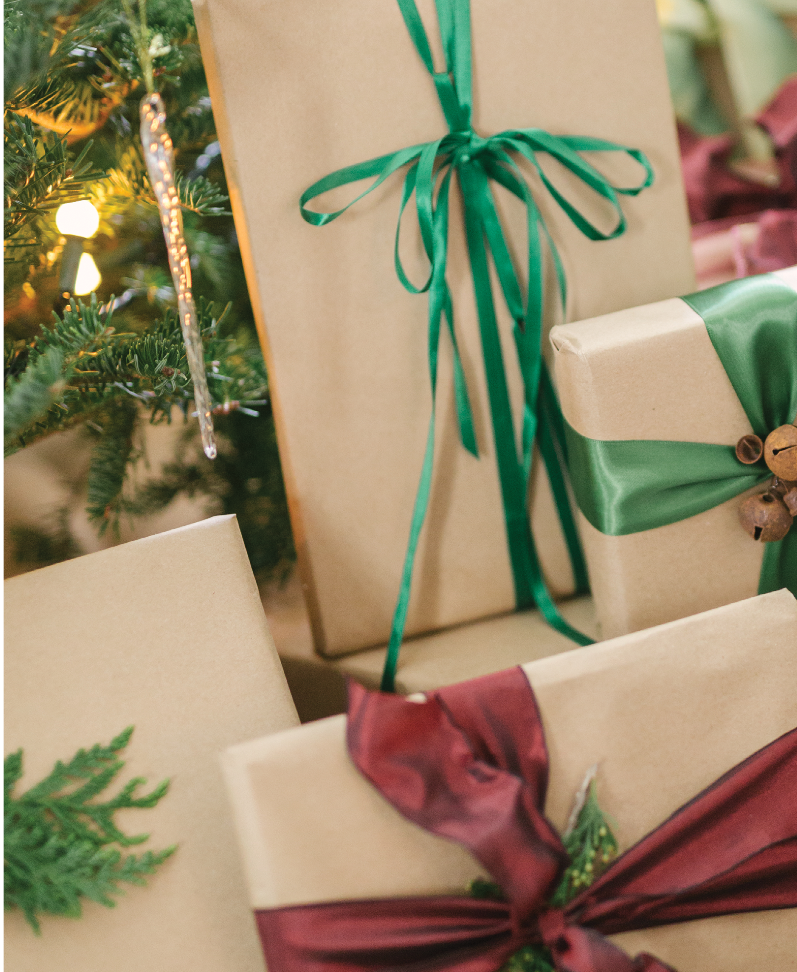 Color-coordinated gifts are wrapped in kraft paper and embellished with satin ribbon and an organic element, such as a snippet of fir, a cinnamon stick, acorns, or berries.