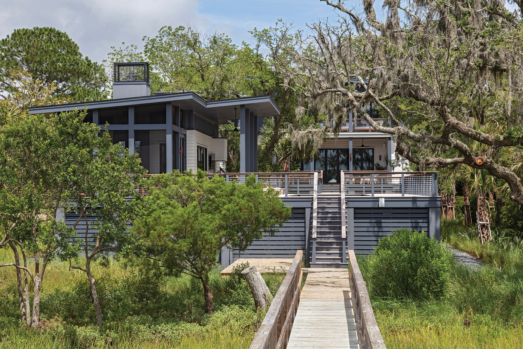 Natural fit: David and Sonya Dunn swapped life on a sailboat for an idyllic lot on James Island. Architecture firm Rush Dixon designed a modern coastal residence that embraces the river views and puts outdoor living front and center, courtesy of a spacious pool house, plenty of porches, and deck space.