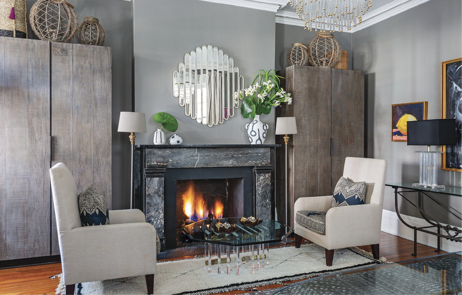 After dinner, the family turns their chairs to enjoy a fireside dessert by the glass and Lucite coffee table (also Patricia Allen Antiques). Restoration Hardware wall cabinets provide ample storage for this multipurpose room.