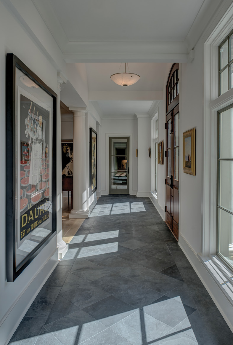 WELL FRAMED: Parallel linear foyers with floating walls to accommodate large paintings, bookend the main living area. Underscoring the home’s symmetry, they provide excellent gallery space, this one showcasing vintage French Art Deco posters of Lotti, Cappiello, and Falcucci.