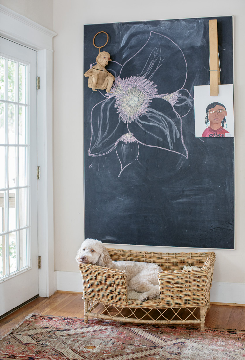 Doodle Approved: The wicker bed belonging to Ruby the Labradoodle sits beneath a chalkboard for family messages and artwork, such as 12-year-old Lily’s self-portrait.