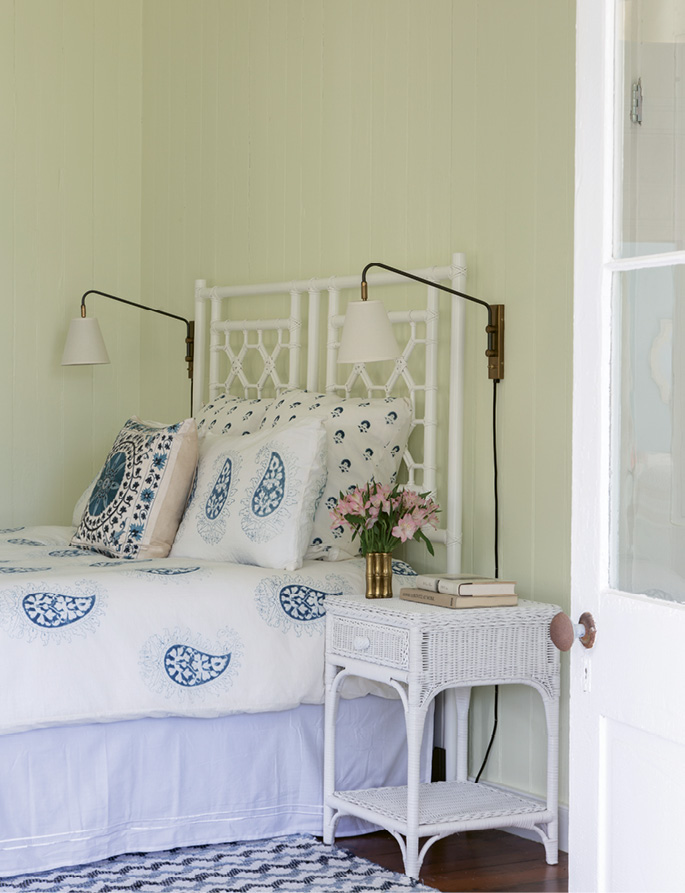 ...where a vintage white wicker headboard and table brighten the smaller space.