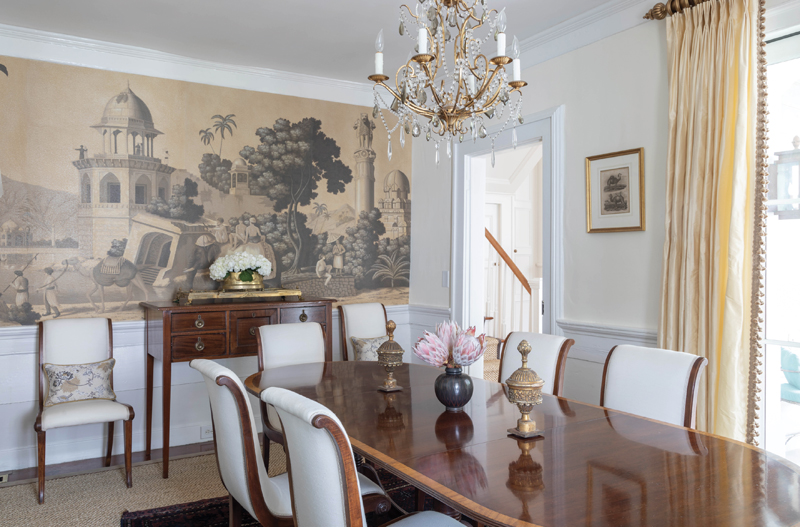 In the 18th-century home’s narrow dining room, one wall covered in custom panels of de Gournay’s “Early Views of India” wallpaper is the scene stealer.