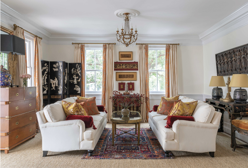 Alexandra Howard looked to her family’s collection of Asian antiques and artifacts to define the look and feel of this sitting room. A set of framed Indian sandalwood friezes and a trio of Chinese bas-reliefs inspired its rich red-and-gold color palette