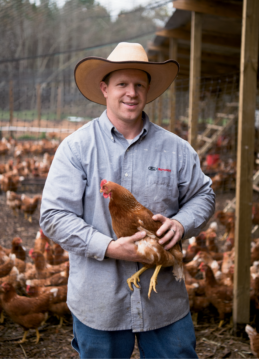 Storey holds one of his 3,000 birds inside a free-range grazing pen.