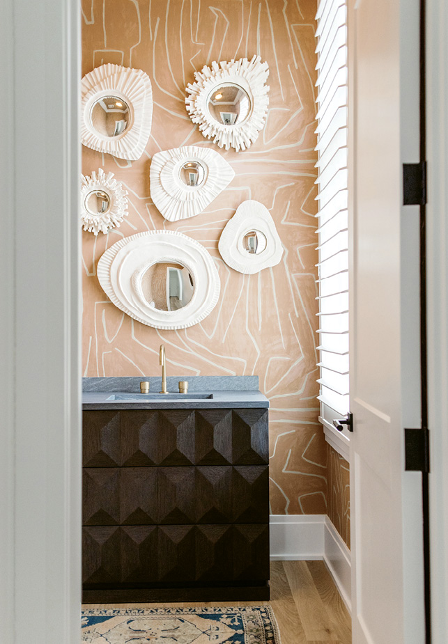 With its graphic wallpaper and plaster mirrors, the powder room packs a punch.