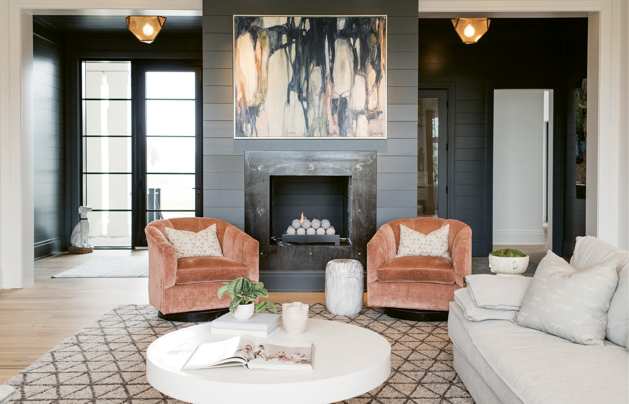 The moody foyer, crushed velvet chairs, and abstract painting by Jill Pumpelly add depth to the living room’s neutral palette.