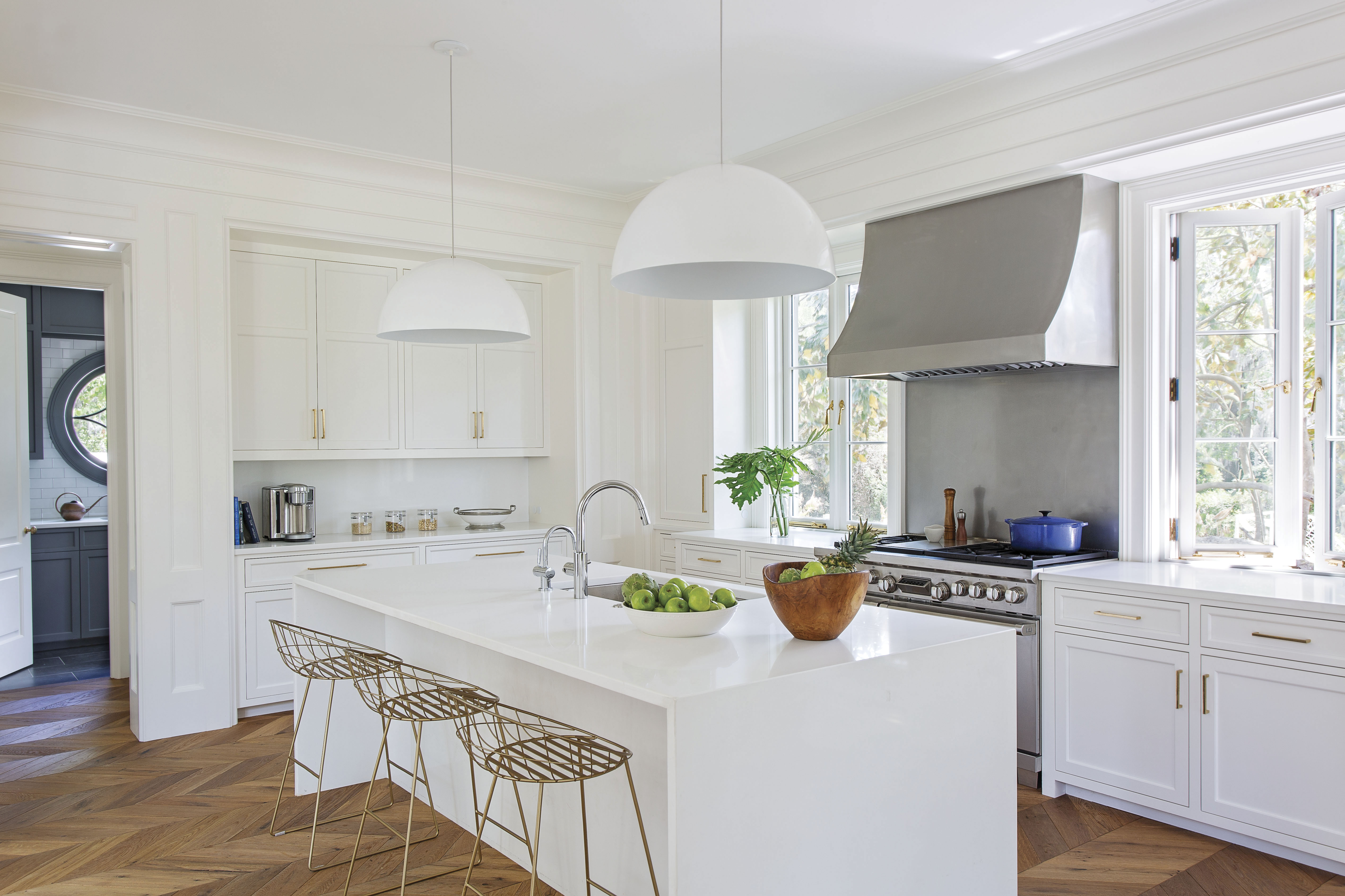 In the kitchen, Benjamin Moore “Simply White”-painted walls allow the stainless steel Wolf stove to pop against quartz countertops.