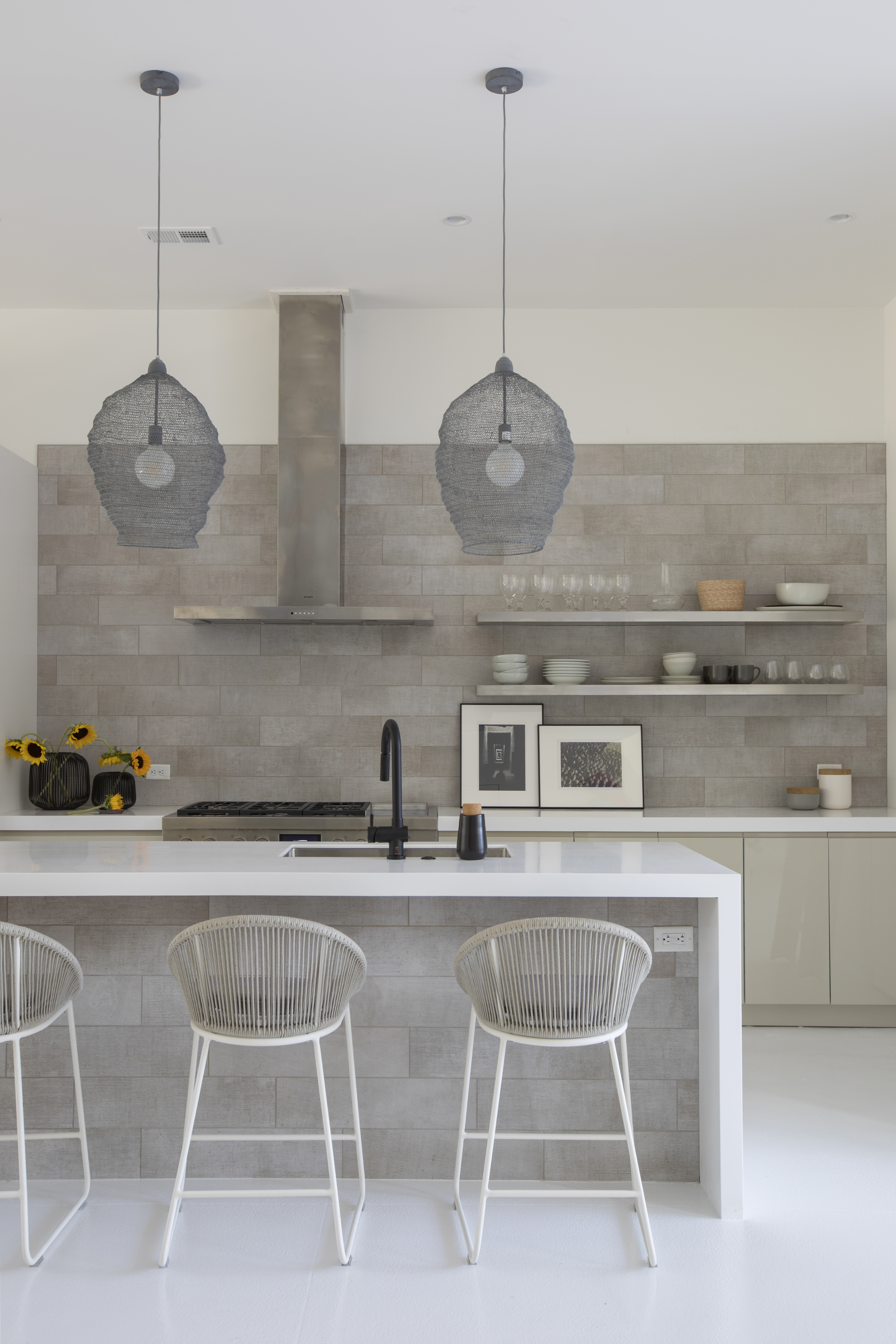 The tile—ceramic with a burlap feel on the wall and island—offers a textural backdrop for the high gloss cabinetry and matte Corian countertops.