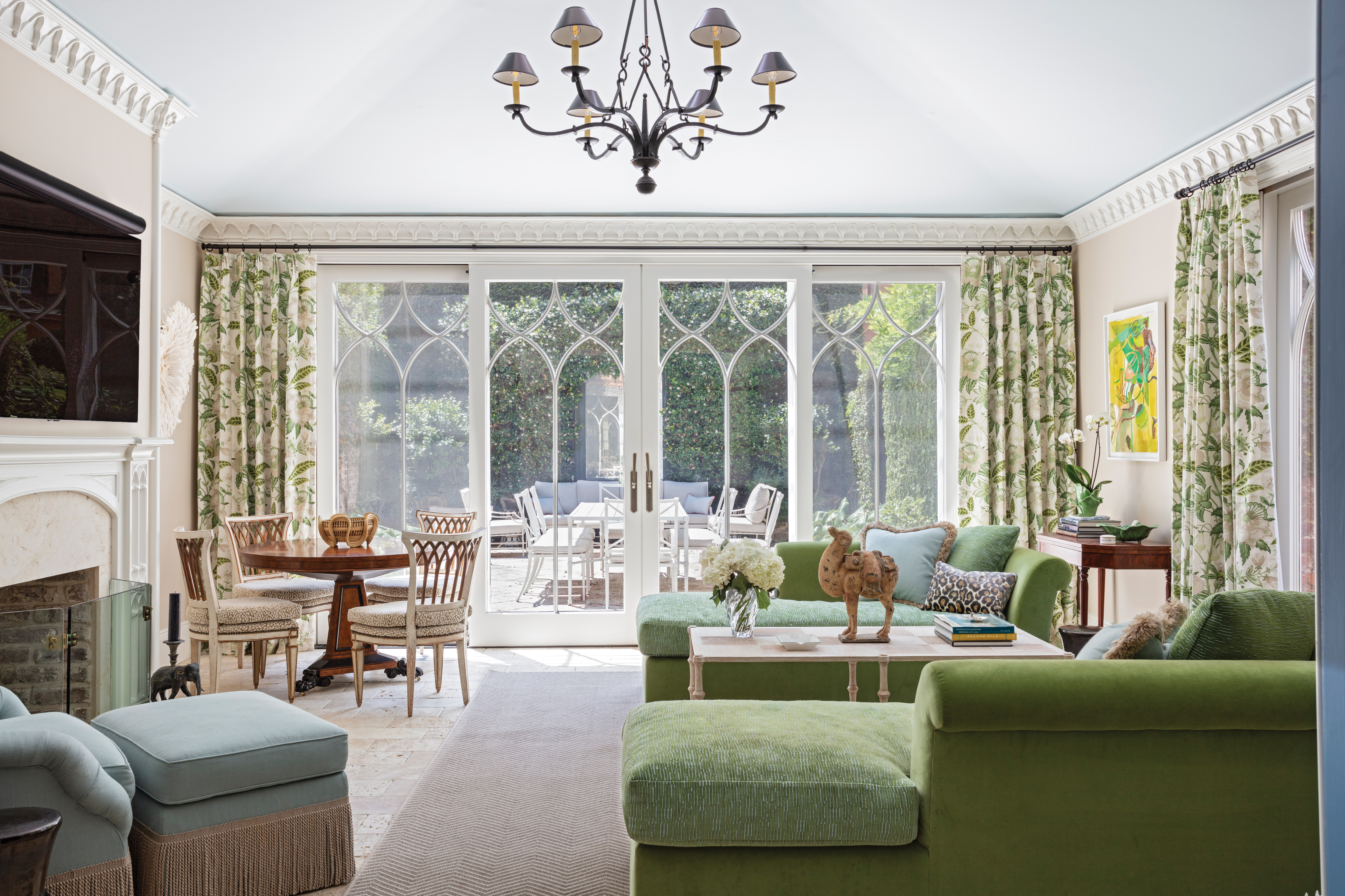 Verdant Views: The garden room, a 21st-century addition, has a bigger brighter feel. Here, Killian opted for lighter colors on the walls and ceiling balanced with deep green velvet fabrics on the chaises and delightful Lee Jofa “Davenport Print” linen curtains in “Greenery.”