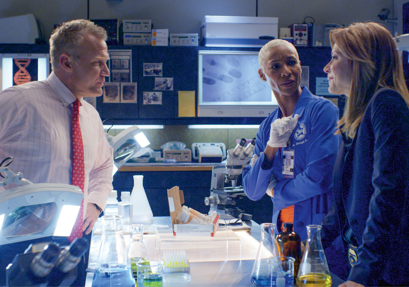 The Inspectors’ cast includes (above, left to right) Terry Serpico, Charmin Lee, and Jessica Lundy, shown in the “crime lab.”