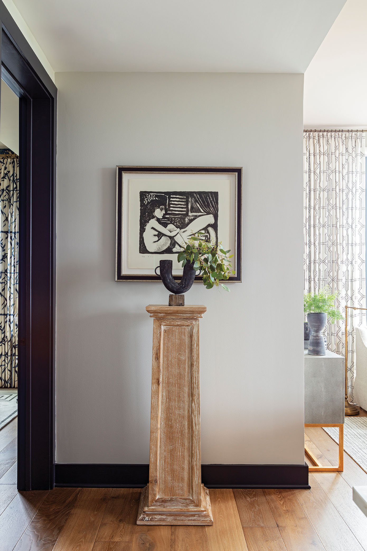 A pedestal from CB2 showcases a Kalalou vase backed by an original painting by Dutch contemporary artist Erik Renssen.