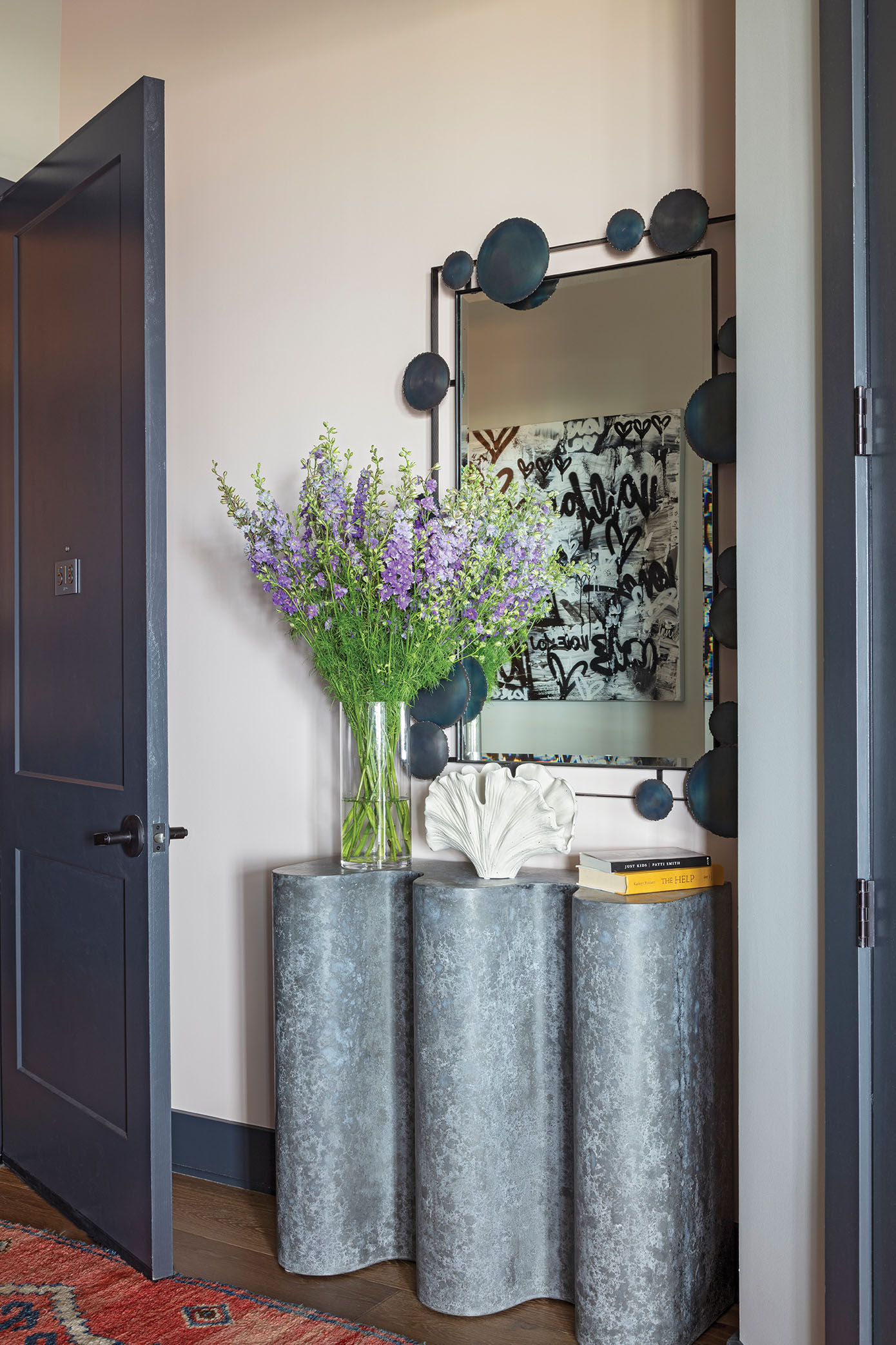 Form fitted: A striking sculptural entry console from Slate Interiors in Charlotte is topped by an Arteriors mirror, reflecting the original artwork by Amber Goldhammer on the opposite wall.