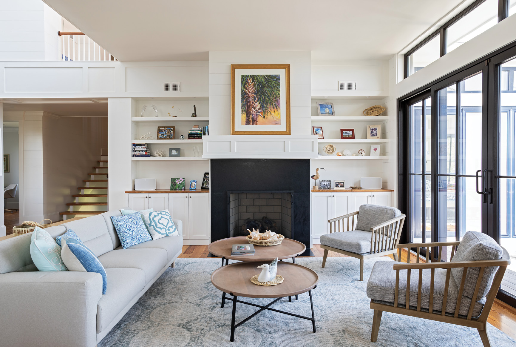 Lighten Up: The second floor embraces open-plan living with a large sitting room, dining room, and kitchen all flooded with natural light. The clean lines of modern furniture in a neutral color palette are enhanced by natural woods and pops of blue.