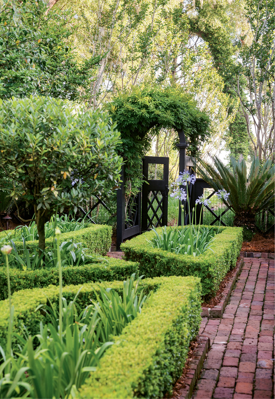 River Walk: A gateway offers an invitation toward the Wappoo through a formal allée edged by crape myrtles and old Charleston brick.