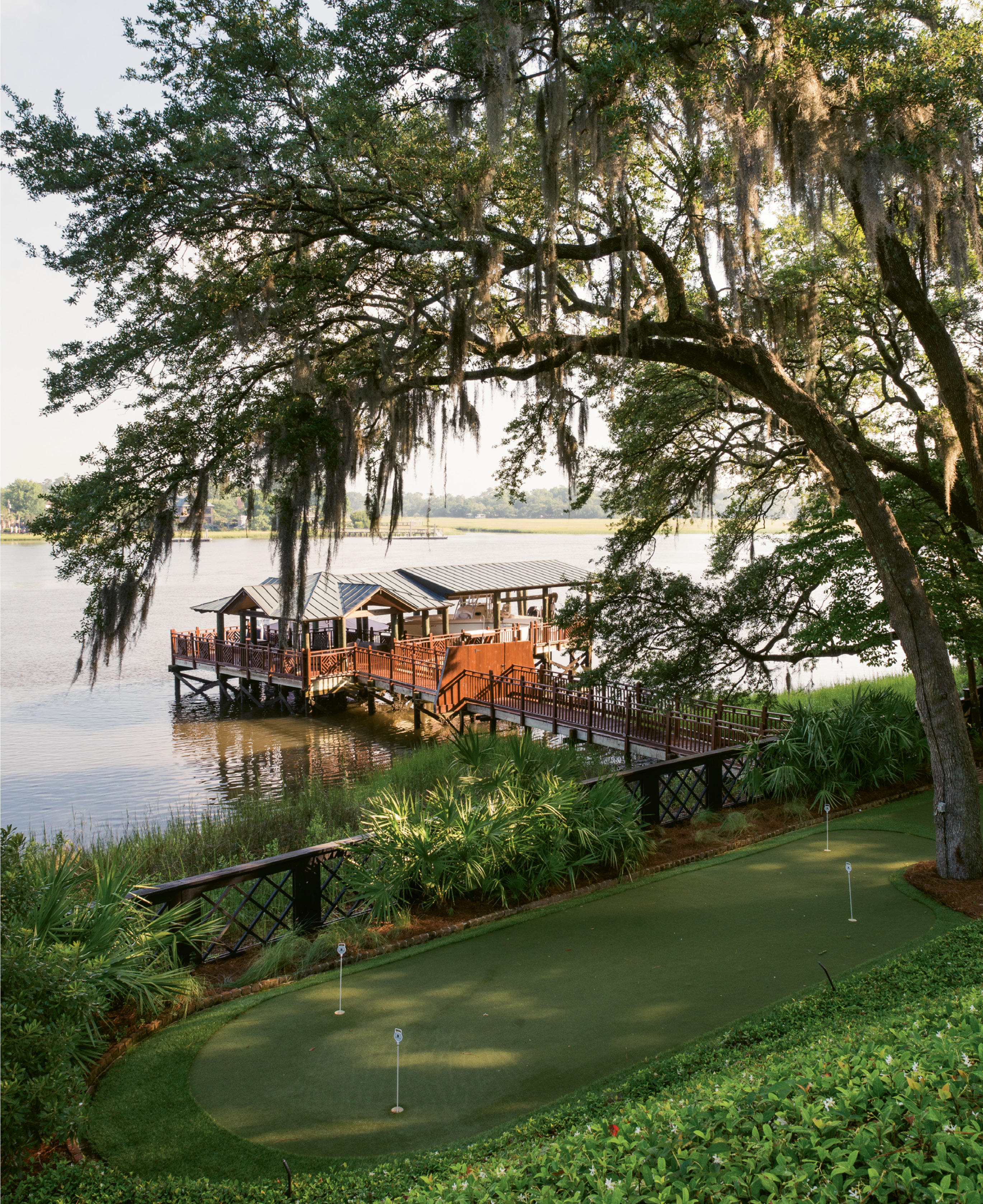 Ground Strokes: Wertimer’s landscaping cascades down to the putting green and dock with a boathouse.