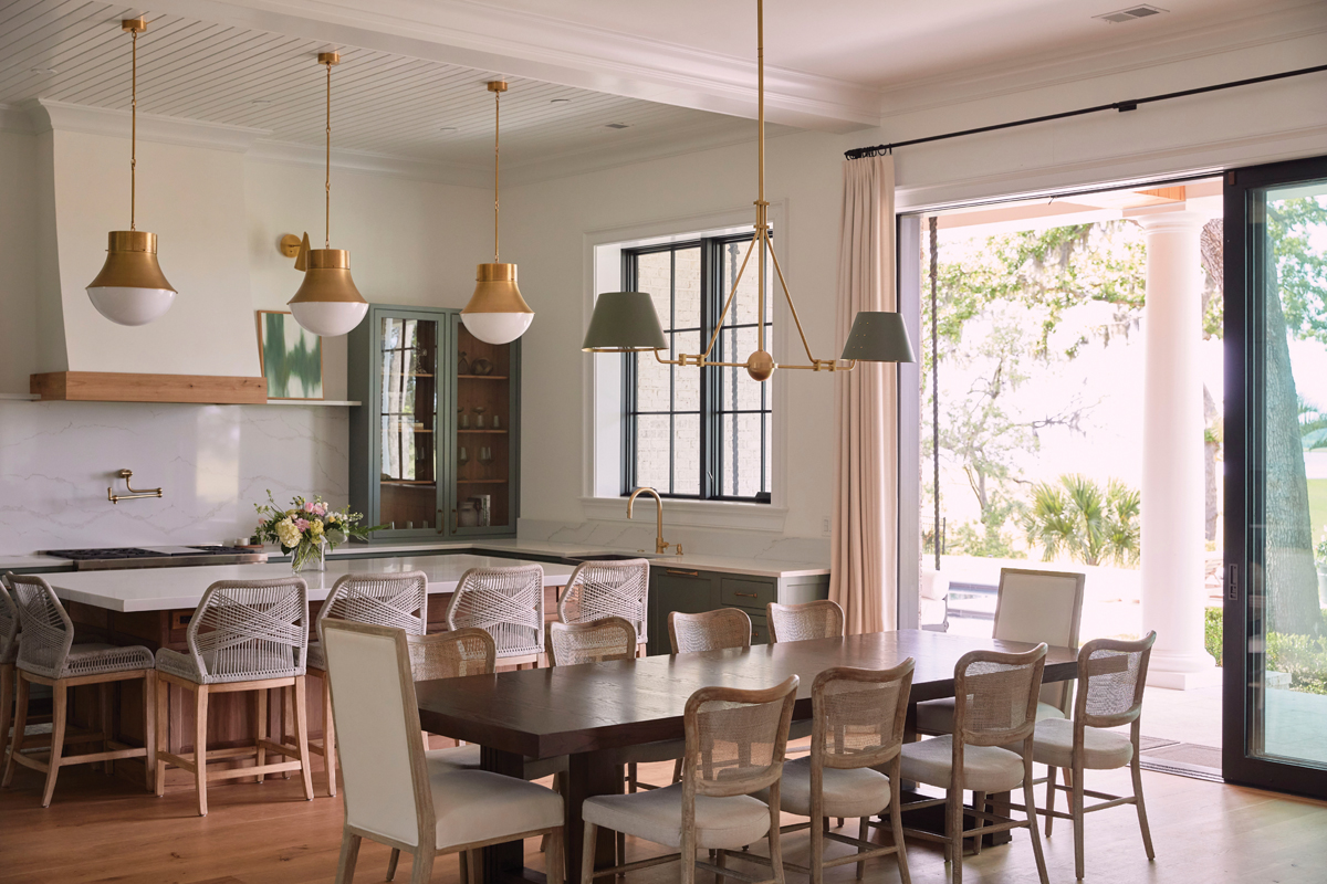 Pops of green throughout tie into the kitchen, where a bleached walnut island and cabinets painted in Sherwin Williams “Rosemary” create an organic vibe. Brass pendant lighting from Visual Comfort adds an element of sophistication.