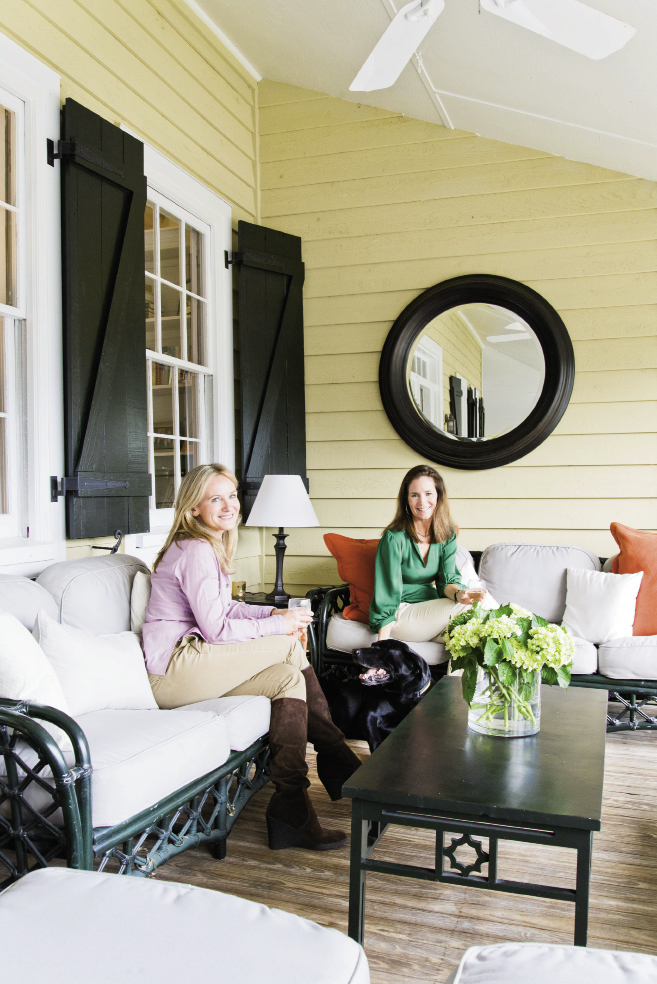 Color Scheme: Nathalie (left) and Jenny relax on the front porch, where they reused Jenny’s outdoor furniture from her old house and simply added orange accent pillows from Carolina Pottery to freshen it up. “When I bought the house, the shutters were bright turquoise,” says Jenny. “We painted them Charleston Green, which is more my style.”